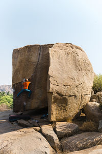 Male rock climber ascending huge boulder