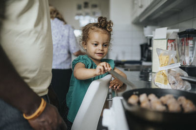 Happy girl looking at meal being cooked by father