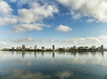 City at waterfront against cloudy sky