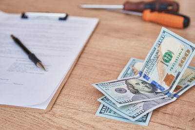 Document, pen and dollar bills on the table, close up