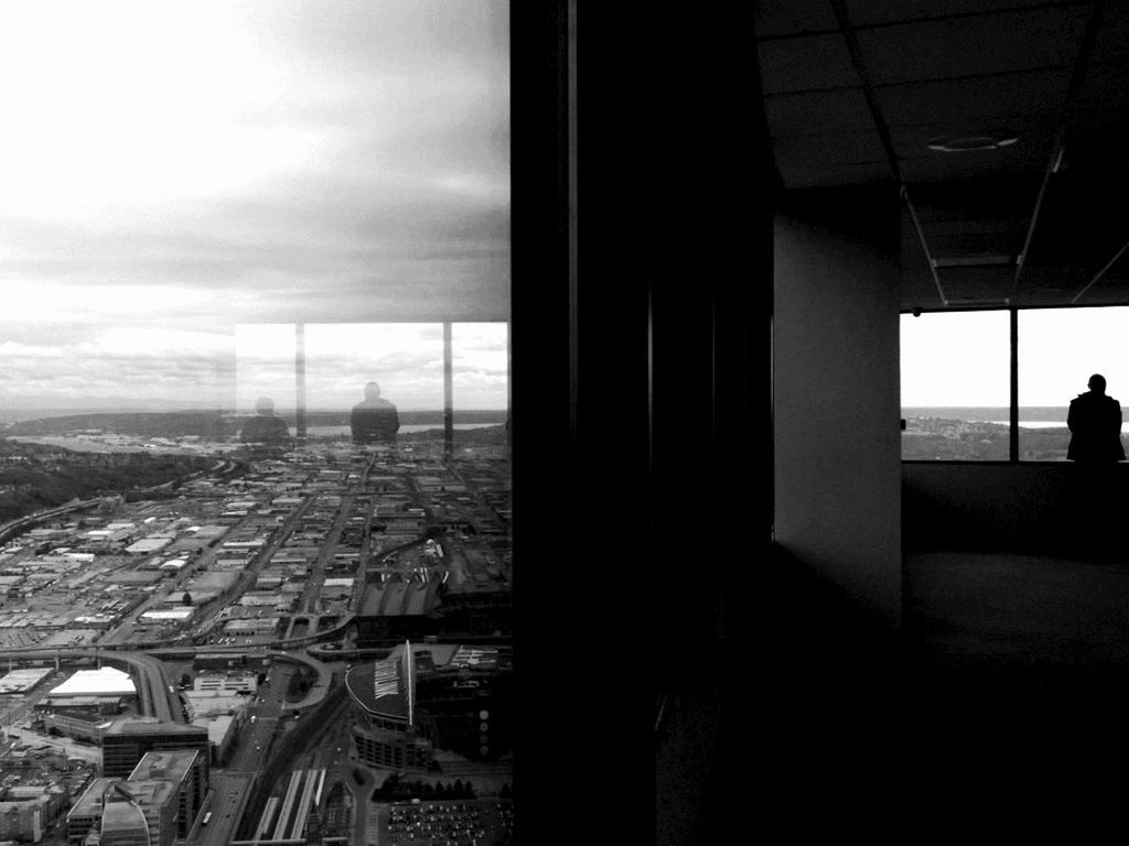 architecture, indoors, built structure, window, sky, glass - material, building exterior, transparent, silhouette, cloud - sky, city, sunlight, cityscape, day, looking through window, no people, building, architectural column, cloud, shadow