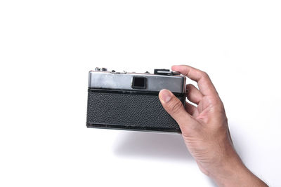 Close-up of hand holding camera against white background