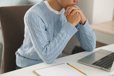 Midsection of man using mobile phone while sitting on table