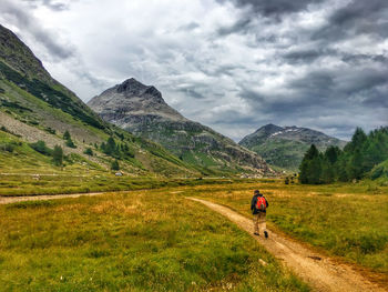 Rear view of man walking on mountain road against sky