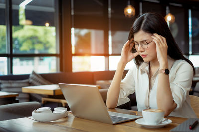 Woman using phone while sitting on table