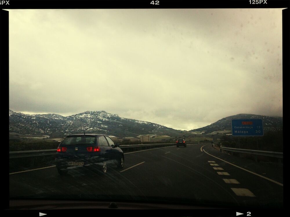 transportation, car, land vehicle, transfer print, mode of transport, road, mountain, sky, auto post production filter, road marking, cloud - sky, the way forward, mountain range, travel, highway, weather, on the move, street, winter, snow