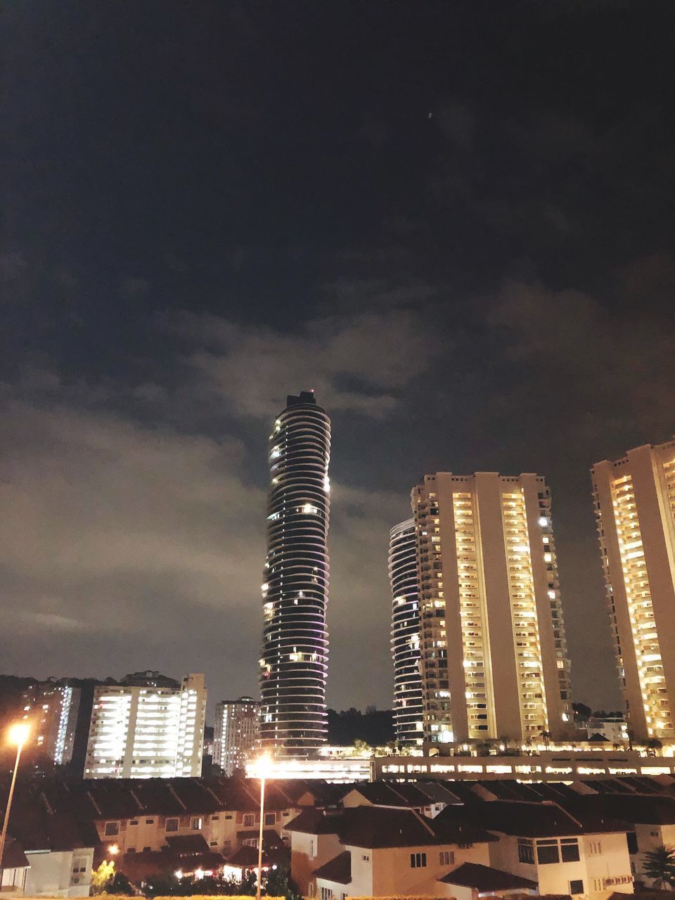 LOW ANGLE VIEW OF ILLUMINATED BUILDINGS AGAINST SKY DURING NIGHT