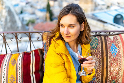 Woman is enjoying the glass of wine on the balcony at sunset