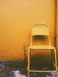 Abandoned chair against wall