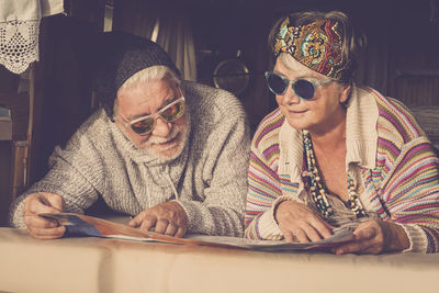 Couple wearing sunglasses reading map while lying in motor home