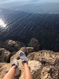 Low section of person on rock by sea