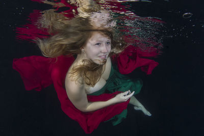 Beautiful young woman swimming in pool at night