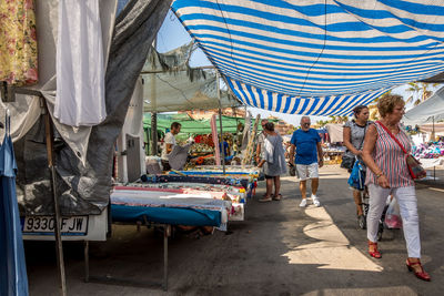 Rear view of people walking on street market in city