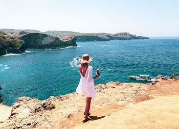 Woman standing by sea against sky