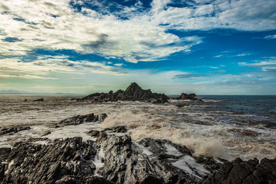 Rocky sea beach with crashing waves at morning from flat angle
