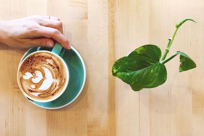 Hand holding coffee cup on table