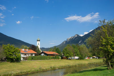 Houses by trees and buildings against sky