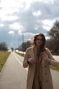 Young woman standing on road against sky