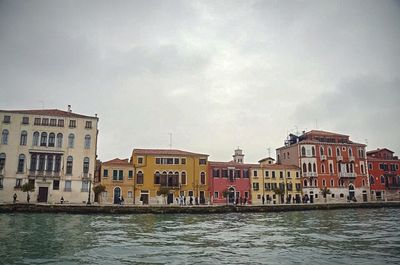 Buildings by canal against sky