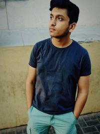 Man looking away while standing against retaining wall