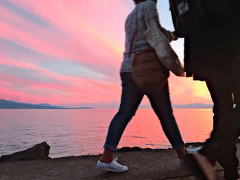 Woman standing on beach against sky during sunset