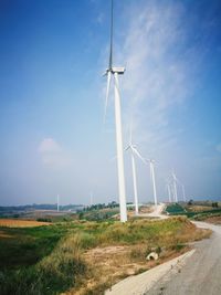 Wind turbines on field against blue sky