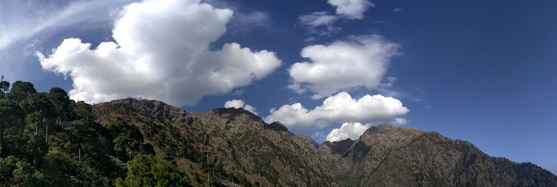 Low angle view of rocky mountains against blue sky