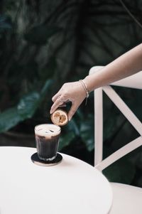 Close-up of hand holding coffee cup on table