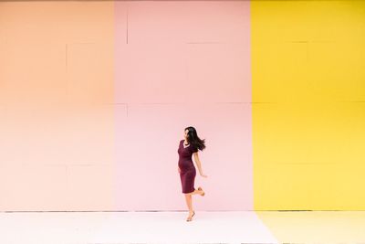 Full length of pregnant woman standing against wall