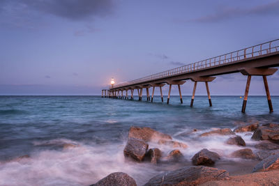 Scenic view of pont del petroli in badalona by mediterranean sea against sky during moon rise