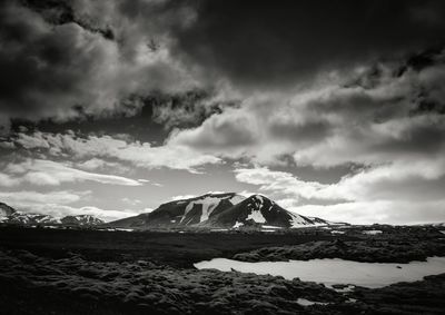 Scenic view of snow covered mountains against cloudy sky