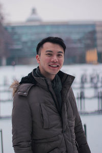 Portrait of smiling young man standing outdoors during winter
