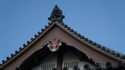 Low angle view of statue against building against clear sky