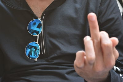 Midsection of man showing middle finger