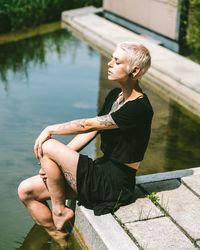 Full length of woman sitting by lake