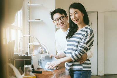 Smiling young woman standing in kitchen at home