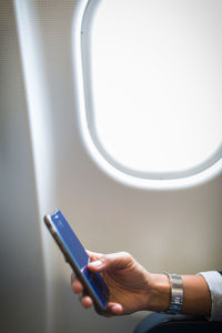 Midsection of man using mobile phone in airplane