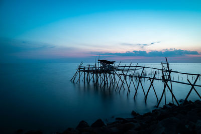 Pier over sea against sky at sunset