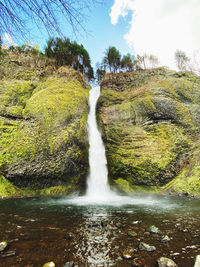 Scenic view of waterfall in forest against sky