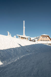 Lighthouse amidst buildings against clear blue sky