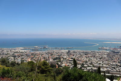 High angle view of townscape by sea against blue sky