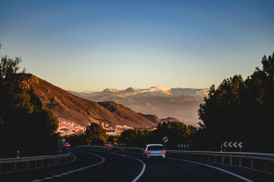 Cars on road against sky during sunset with sierra nevada in the background