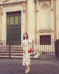 Portrait of woman standing against building