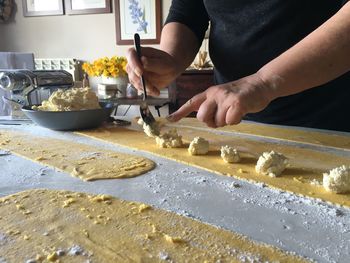 Midsection of person preparing pasta at home