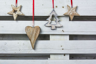 Christmas ornaments hanging against white wooden fence
