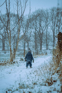 Rear view of man walking on snow covered landscape