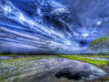 Scenic view of road amidst field against sky