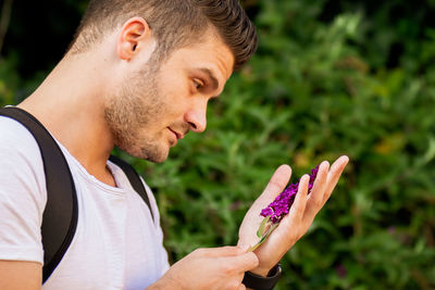 Side view of young man holding purple outdoors