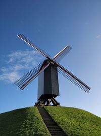 Low angle view of traditional windmill on field against clear sky