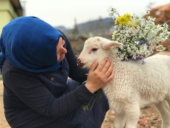 Close-up of woman with lamb and flowers